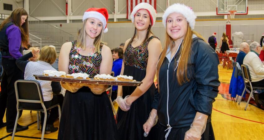 Students in Santa hats serve pumpkin pie